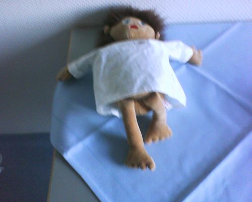 Puppe, bekleidet mit OP-Hemdchen.