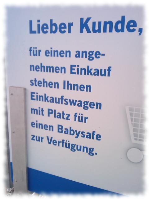 Schild: Lieber Kunde, fr einen angenehmen Einkauf stehen Ihnen Einfauswagen mit Platz fr einen Babysafe zur Verfgung