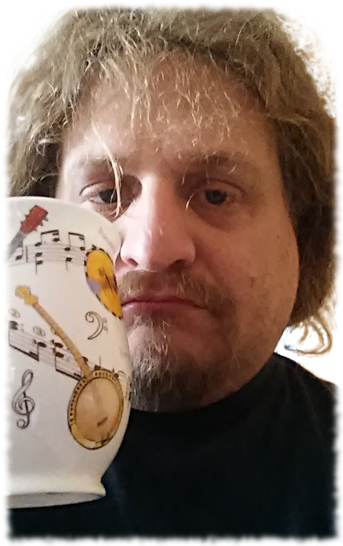 Tee trinken aus einer neuen, mit Zupfinstrumenten verzierten Tasse.
