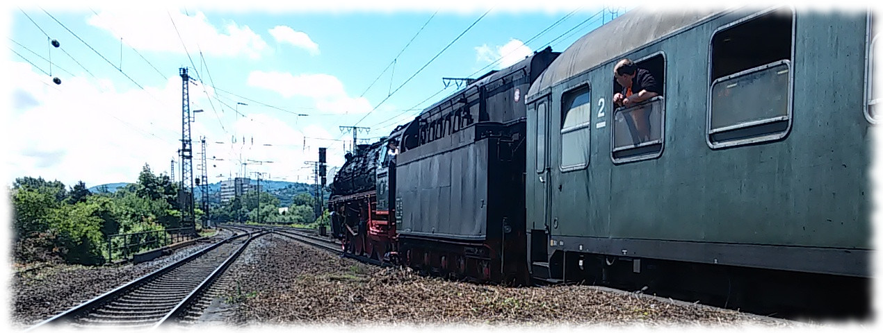 Sonderzug mit Dampflok 01 1066 von hinten im Bahnhof von Koblenz-Ltzel, im Vordergrund alter Reisezugwagen, aus dem jemand aus dem geffneten Fenster guckt. 