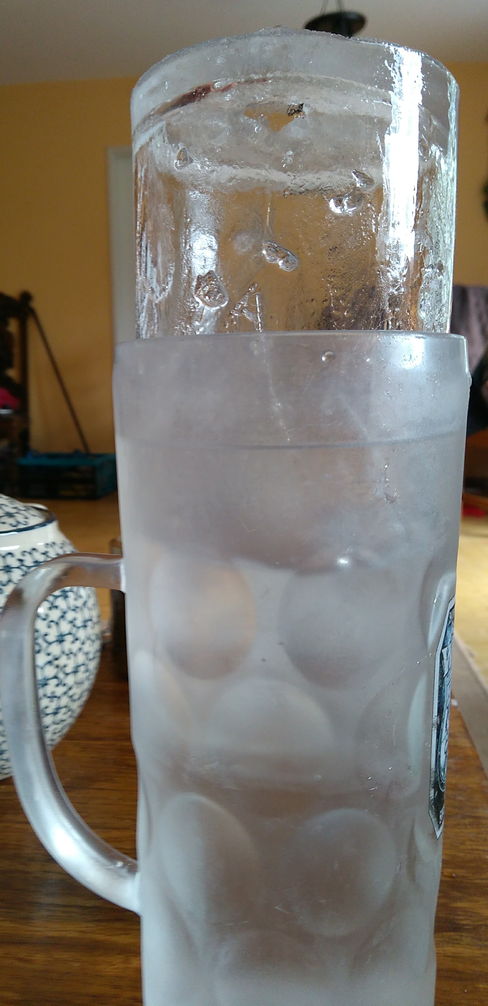 hochgezogener Eiszylinder in groem Wasserbecher aus dem Gefrierschrank.